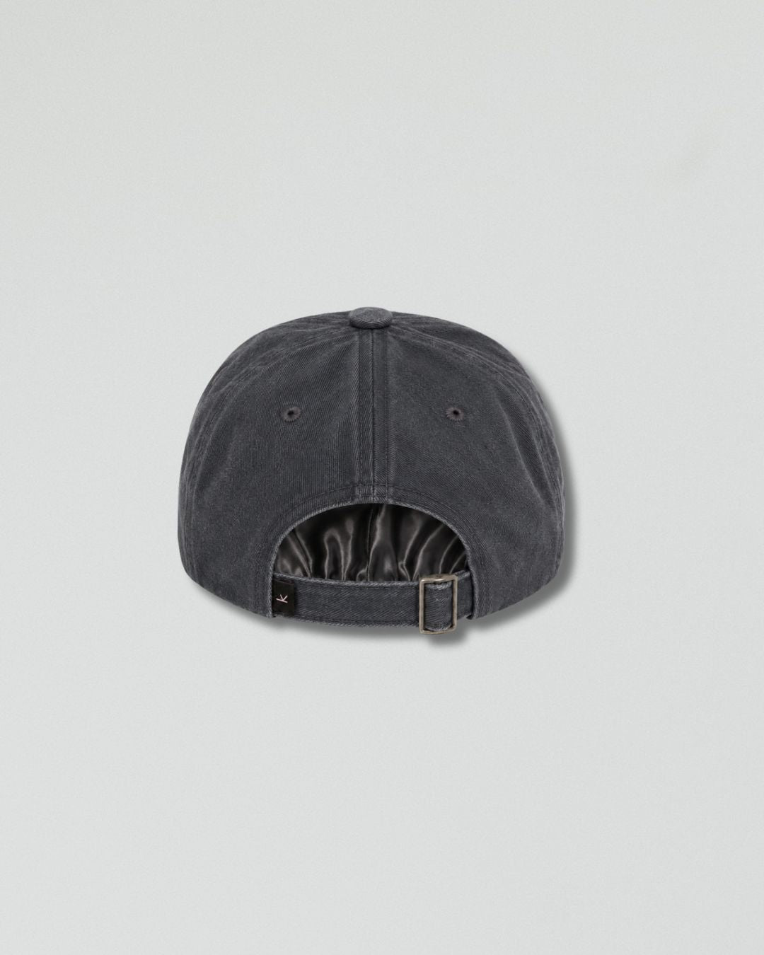 A dark gray washed cotton baseball cap shown from the back, featuring a curved snapback strap with a metal buckle and a small black brand tag on the side, set against a light gray background.