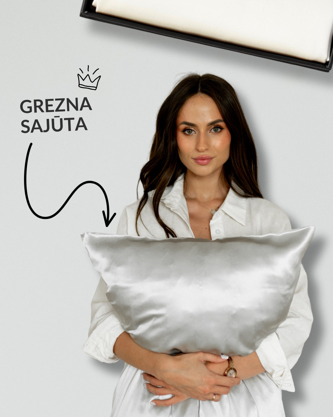 Sieviete baltā kreklā tur rokās baltu zīda spilvendrānu