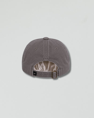 A gray six-panel baseball cap shown from the back, featuring a buttoned top and an adjustable strap with a metal buckle, set against a light gray background.